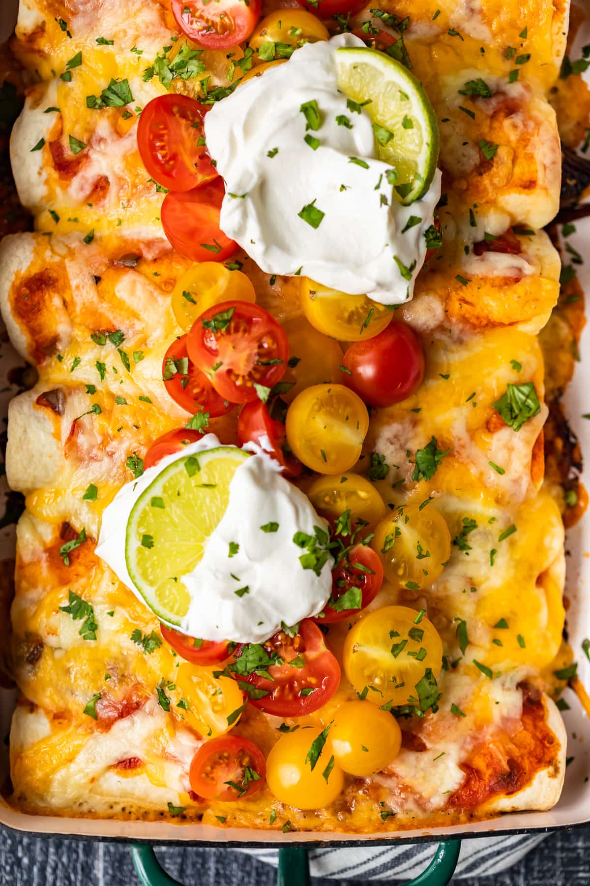 beef enchiladas with sour cream, tomatoes, and cheese