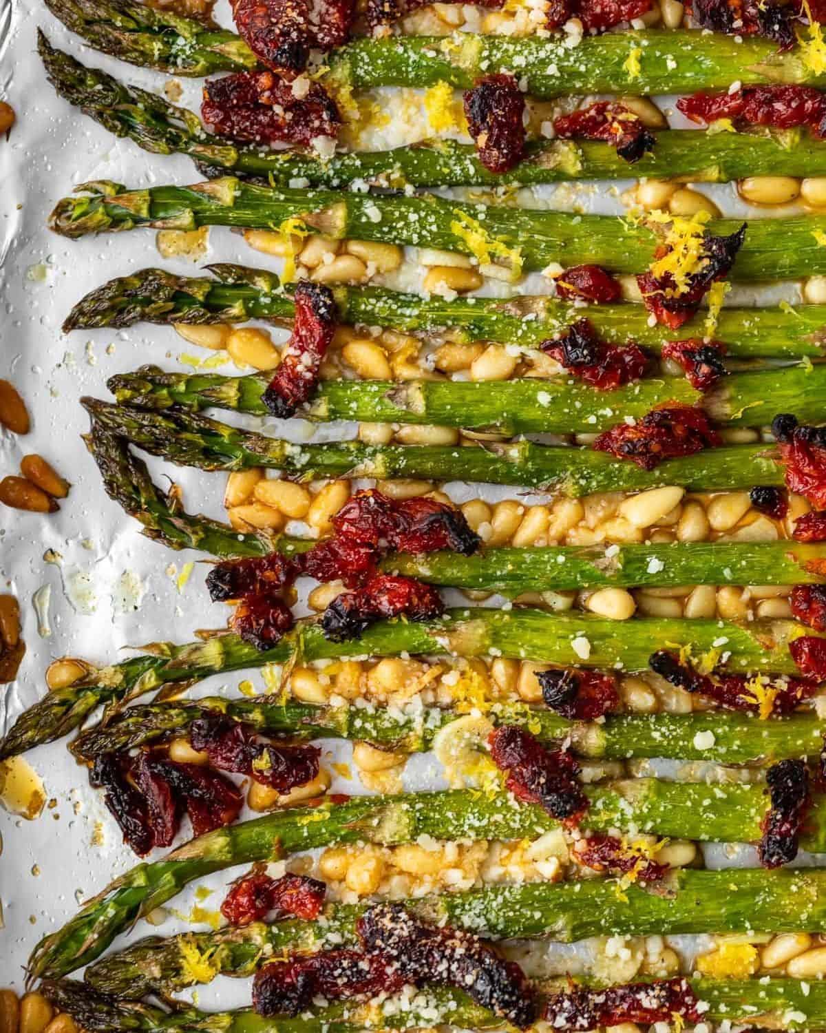 Oven Roasted Asparagus with sun dried tomatoes, pine nuts, garlic, and more is a delicious Mediterranean-inspired side dish fit for any occasion. This easy roasted asparagus recipe is quick to make yet filled with flavor! Add this asparagus side dish to your holiday meals, or just to your weeknight dinners. Either way, it's sure to be a hit! Oven roasted asparagus with sundried tomatoes, pine nuts, and Parmesan cheese.