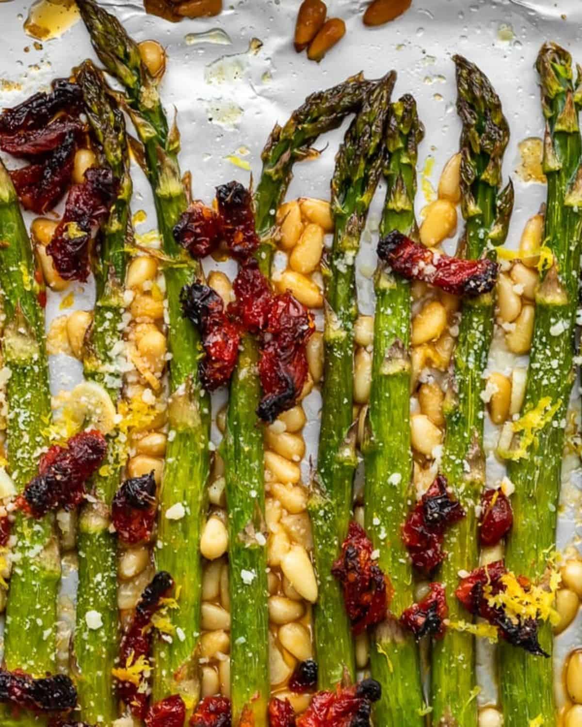 Oven Roasted Asparagus with sun dried tomatoes, pine nuts, garlic, and more is a delicious Mediterranean-inspired side dish fit for any occasion. This easy roasted asparagus recipe is quick to make yet filled with flavor! Add this asparagus side dish to your holiday meals, or just to your weeknight dinners. Either way, it's sure to be a hit! Oven roasted asparagus with pine nuts, and Parmesan cheese.