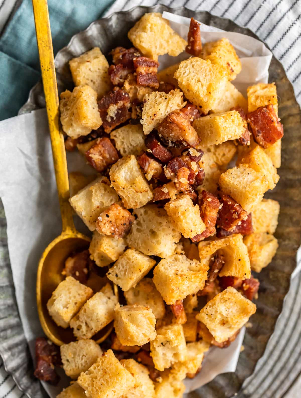 bacon croutons on a serving plate with a gold spoon