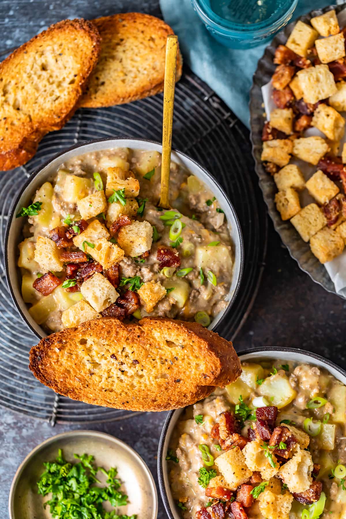 bowls of soup arranged with slices of toasted bread and a plate of croutons