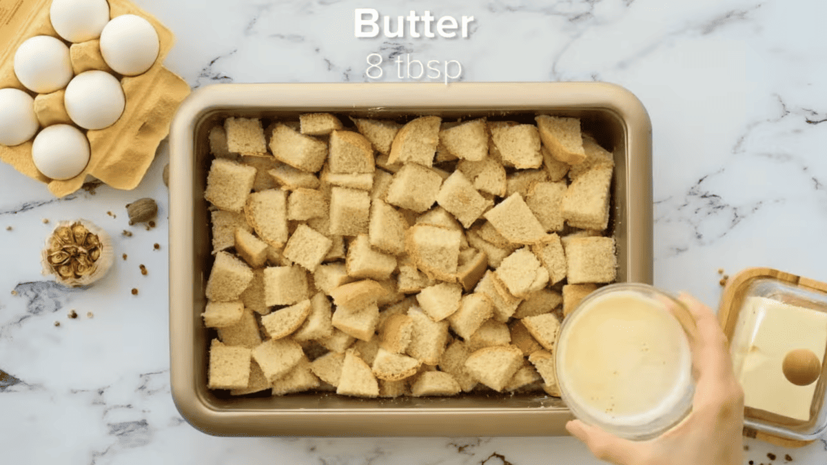 english muffin pieces in a casserole dish topped with melted butter.