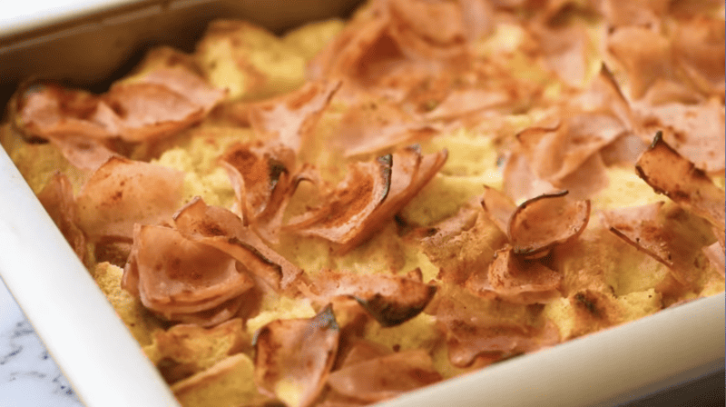 close up view of eggs benedict casserole with crispy ham pieces.