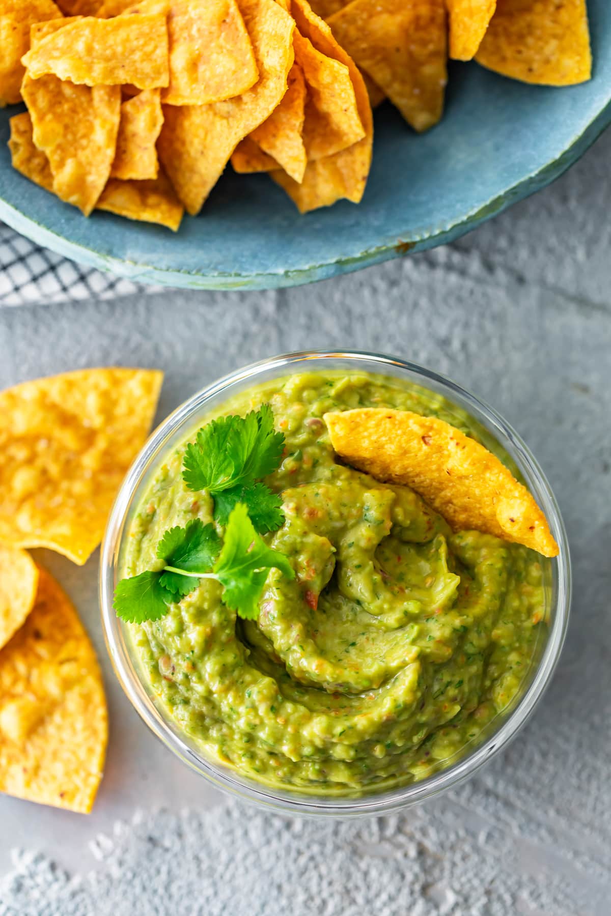 a bowl of guacamole next to a bowl of chips