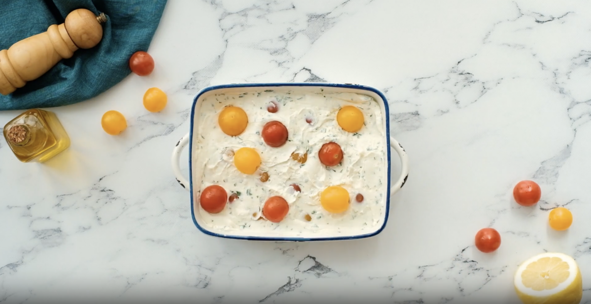 goat cheese dip topped with cherry tomatoes in a baking dish.