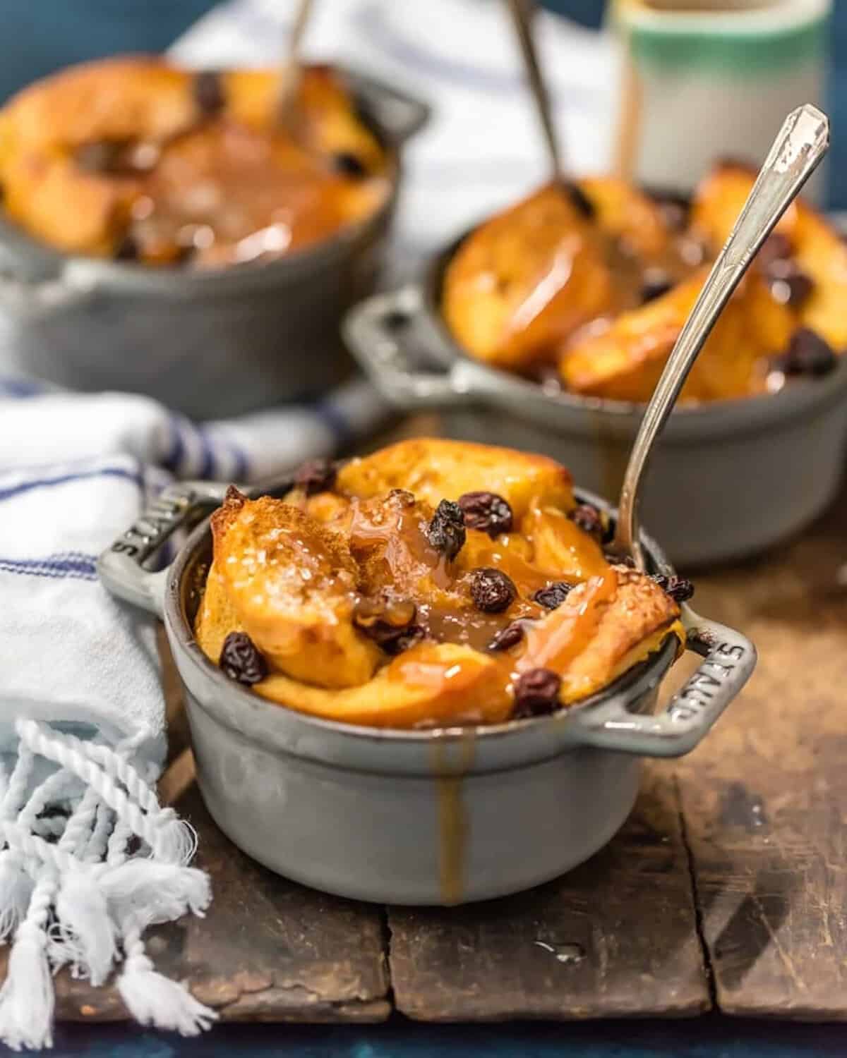 A dish of apple bread pudding with raisins on a wooden board, accompanied by a refreshing St. Patrick's Day punch.