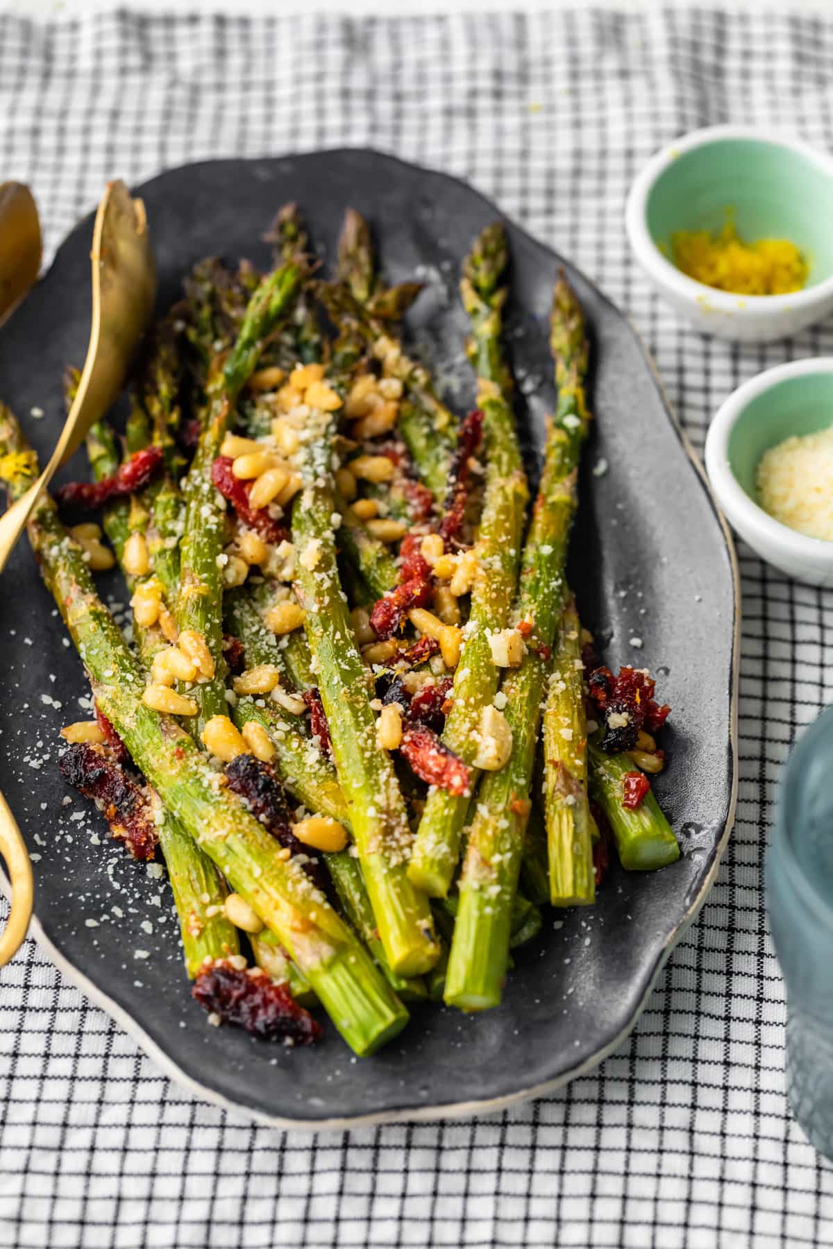 a plate of asparagus mixed with sun dried tomatoes, pine nuts, and more