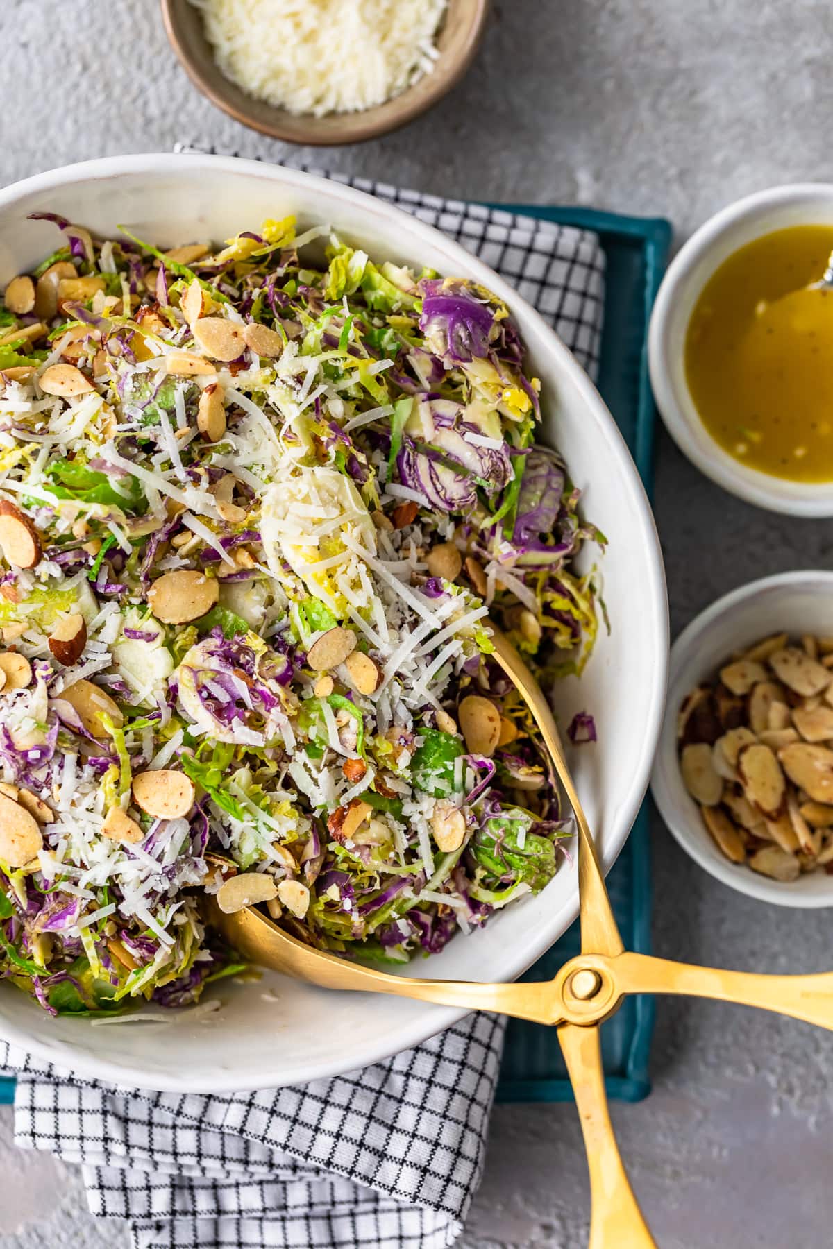 Shaved Brussels Sprout Salad is a simple side dish to serve with any meal. Brussels Sprouts, toasted almonds, and cheese are tossed with a Honey Lemon Dijon Vinaigrette for a light and delicious flavor. This shaved Brussels Sprouts recipe is so easy and can be made in no time! shaved brussels sprout salad in a white bowl