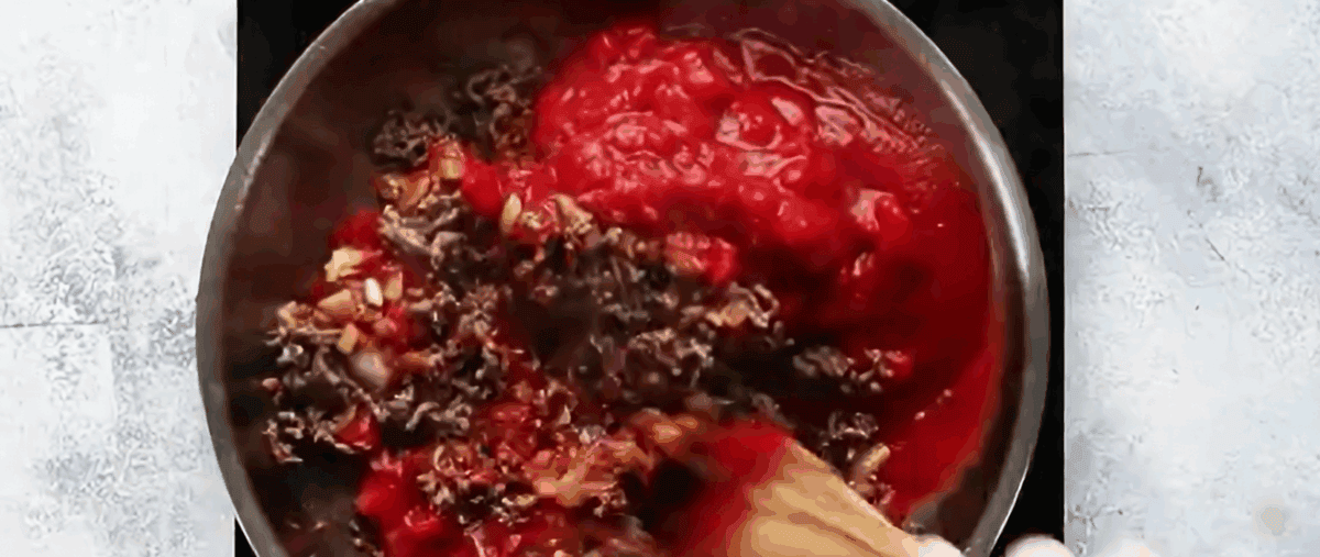 Adding seasonings and tomatoes to the drained ground beef.