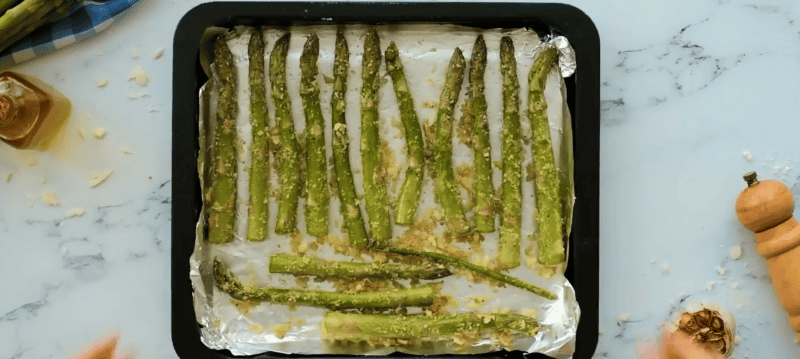 seasoned asparagus on a baking sheet lined with aluminum foil.