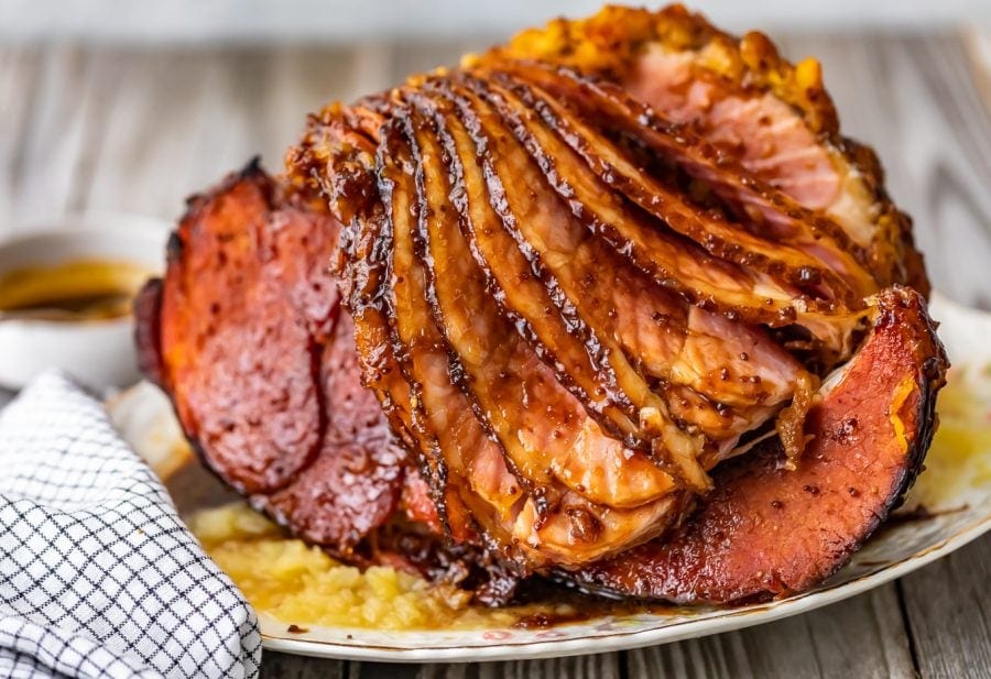 brown sugar glazed spiral ham on a serving platter with pineapple.