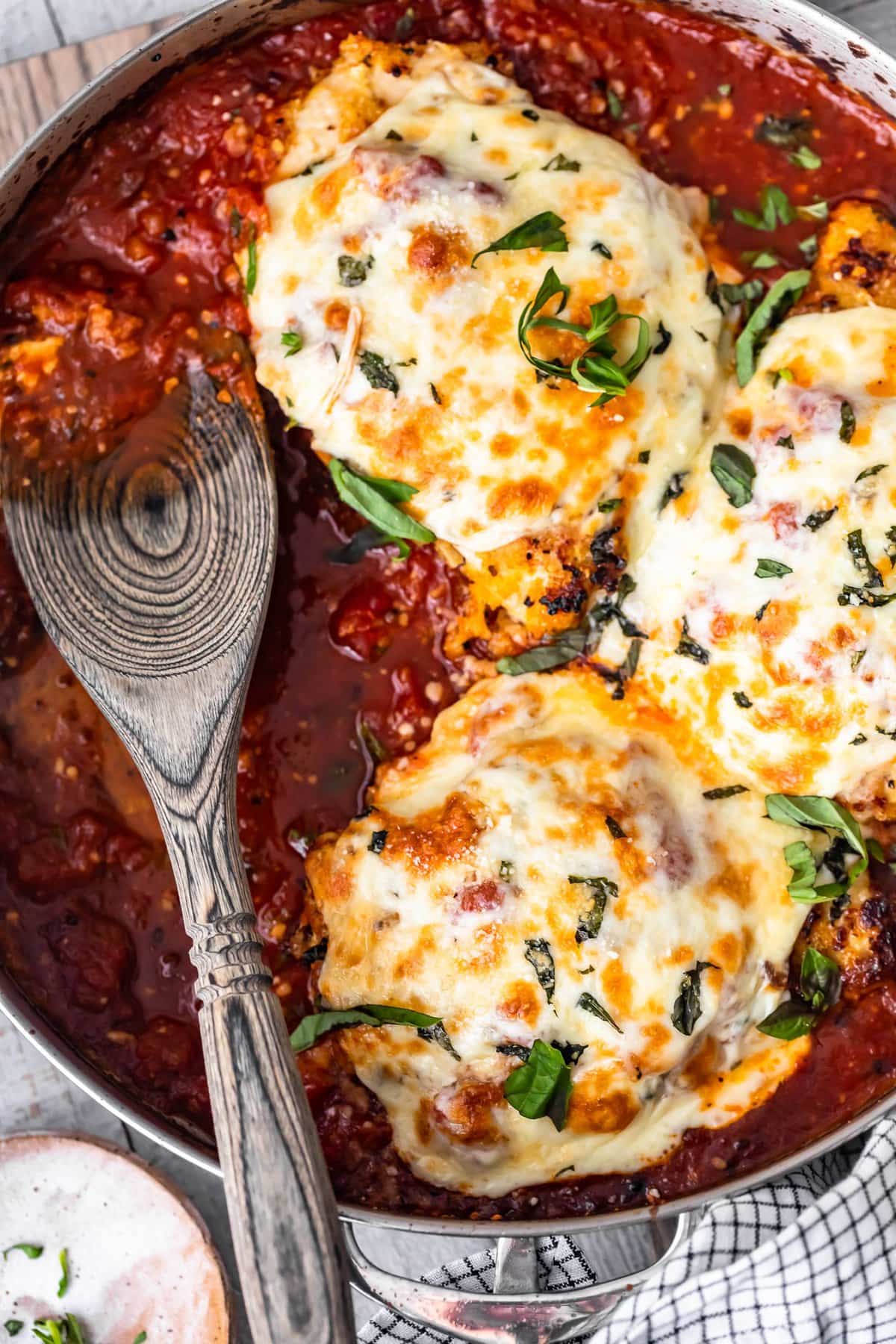 breaded chicken breasts in a skillet filled with marinara sauce