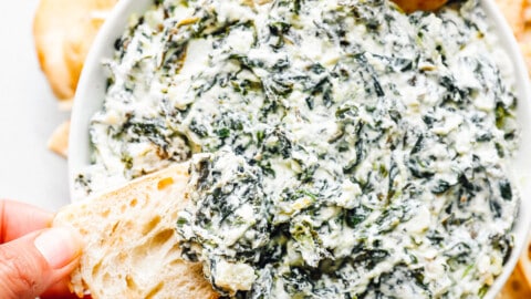 crockpot spinach dip in a white bowl with dippers