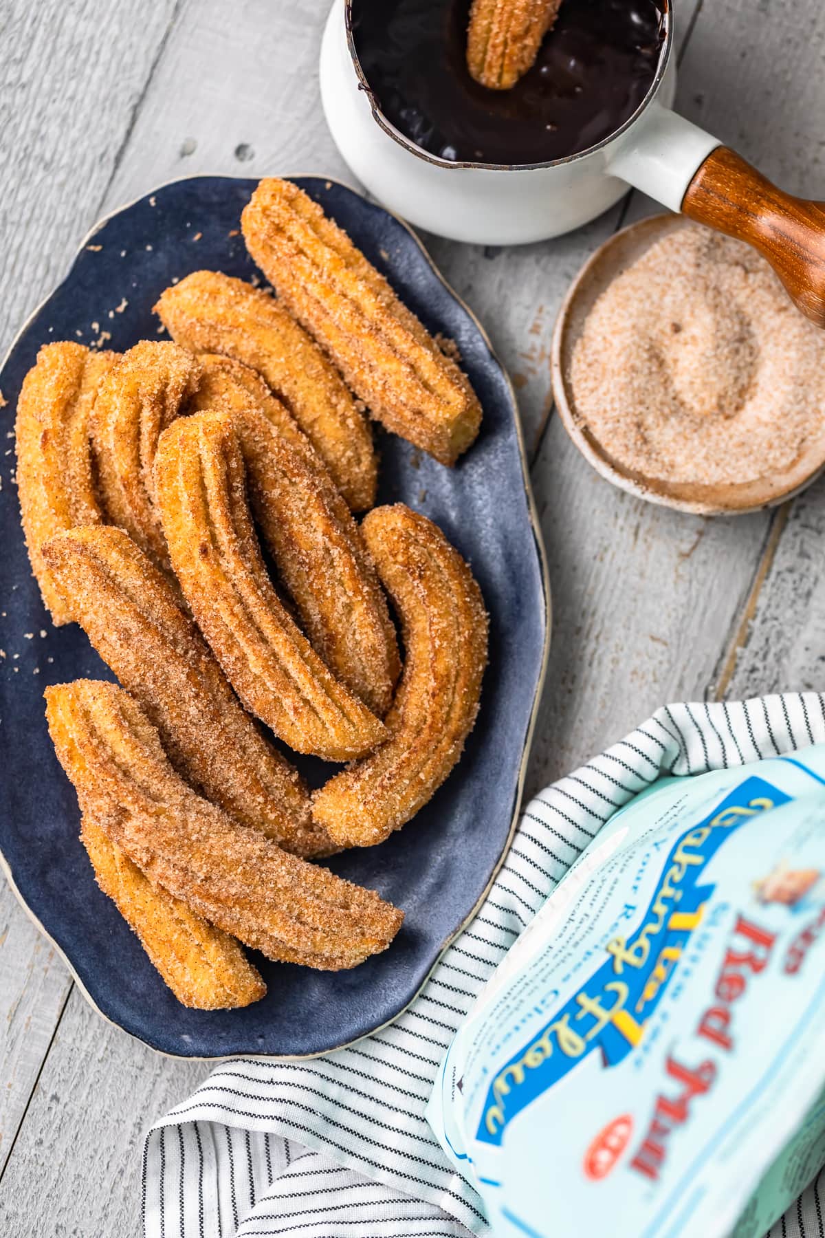 gluten free churros on a plate next to gluten free flour and chocolate sauce