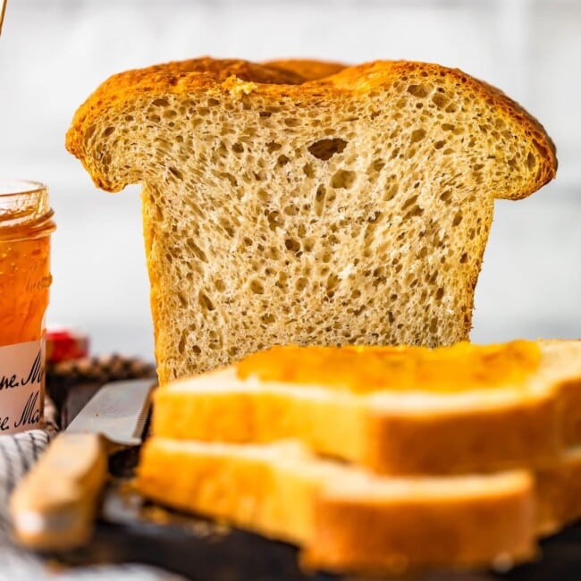 A slice of homemade sandwich bread next to a jar of jam.