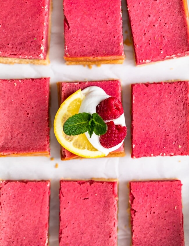 Raspberry Bars are a delicious and easy dessert to serve for any holiday, party, or summer afternoon. These fruity Raspberry Lemon Bars have the perfect flavor, the perfect texture, and the perfect pink color. Top them with some fresh fruit, powdered sugar, and whipped cream for a delightful treat!