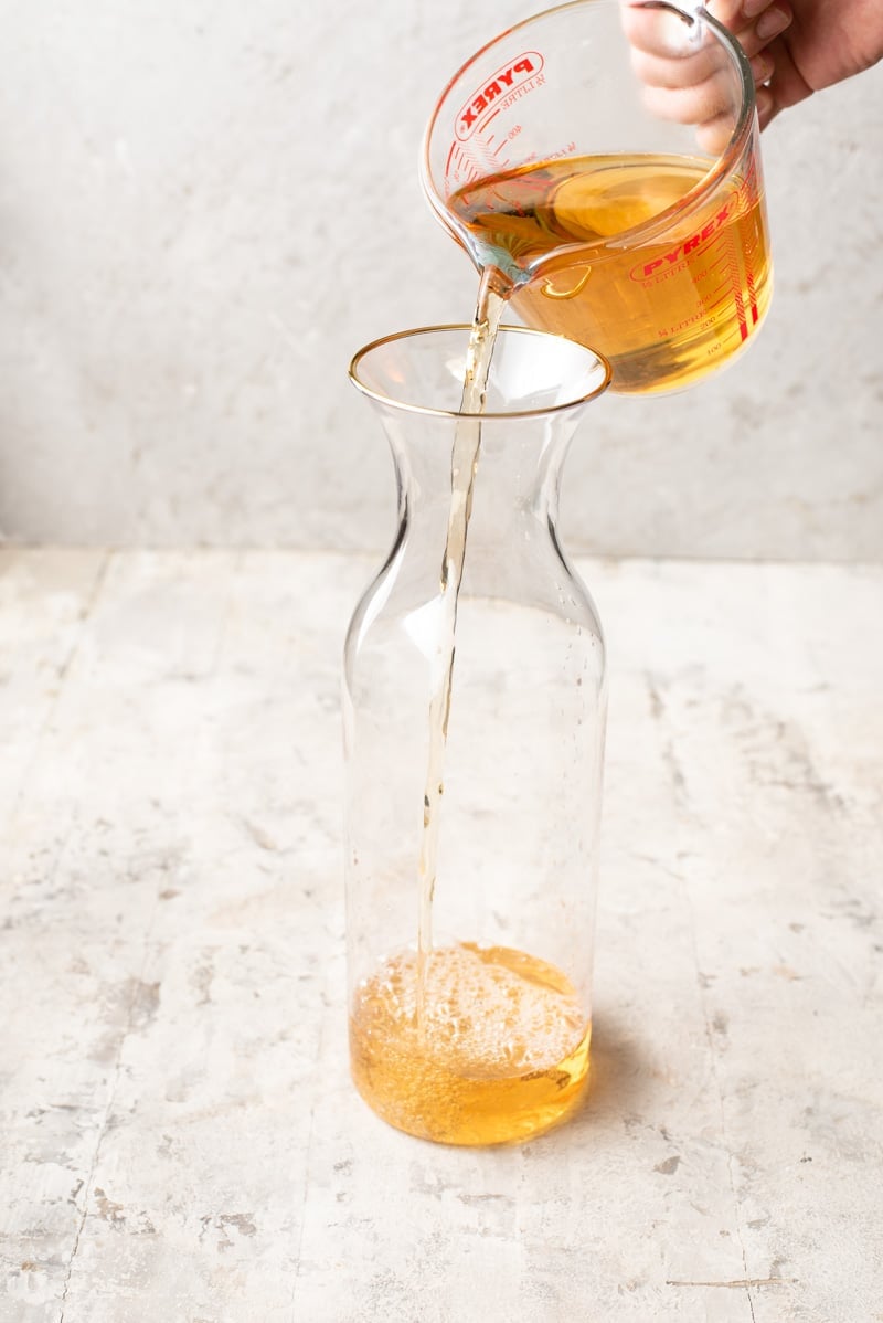 Pouring apple juice into a pitcher.