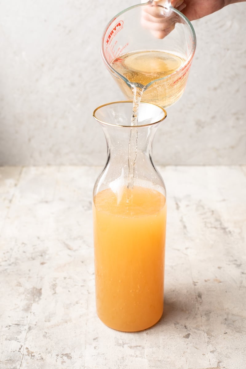 Pouring ginger ale into an apple pie drink pitcher.