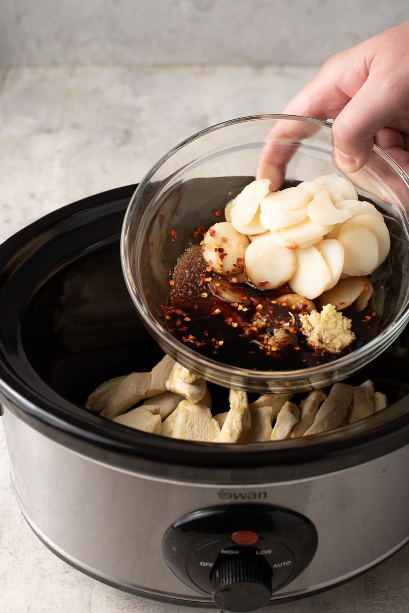Putting ingredients in a slow cooker to make cashew chicken