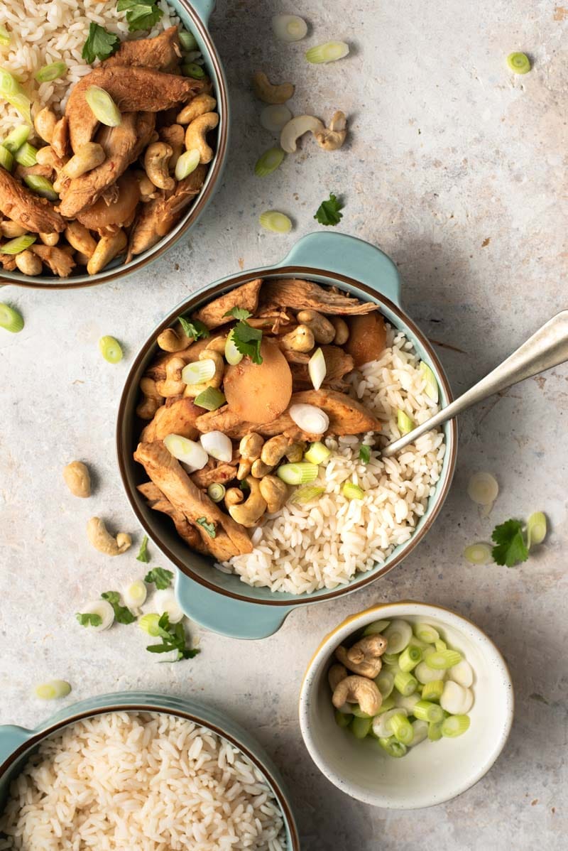 An overhead shot of cashew chicken in blue bowls with rice