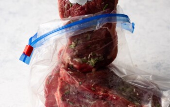 A new york strip steak is being cut out of a plastic bag using a knife.