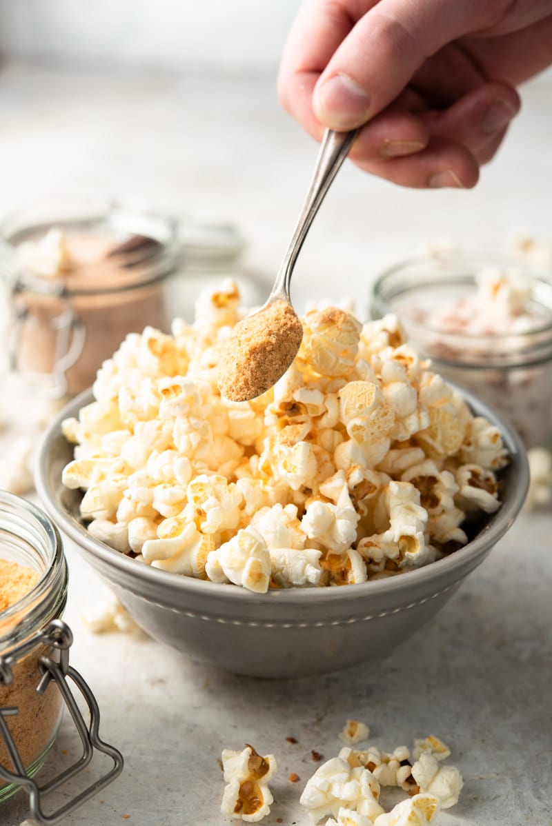 A side shot of popcorn salt getting sprinkled over popcorn