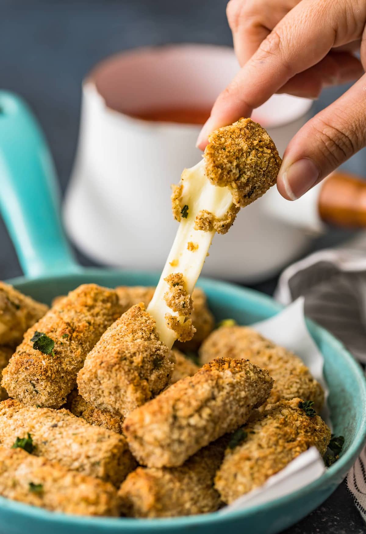 A baked mozzarella cheese stick being broken in half