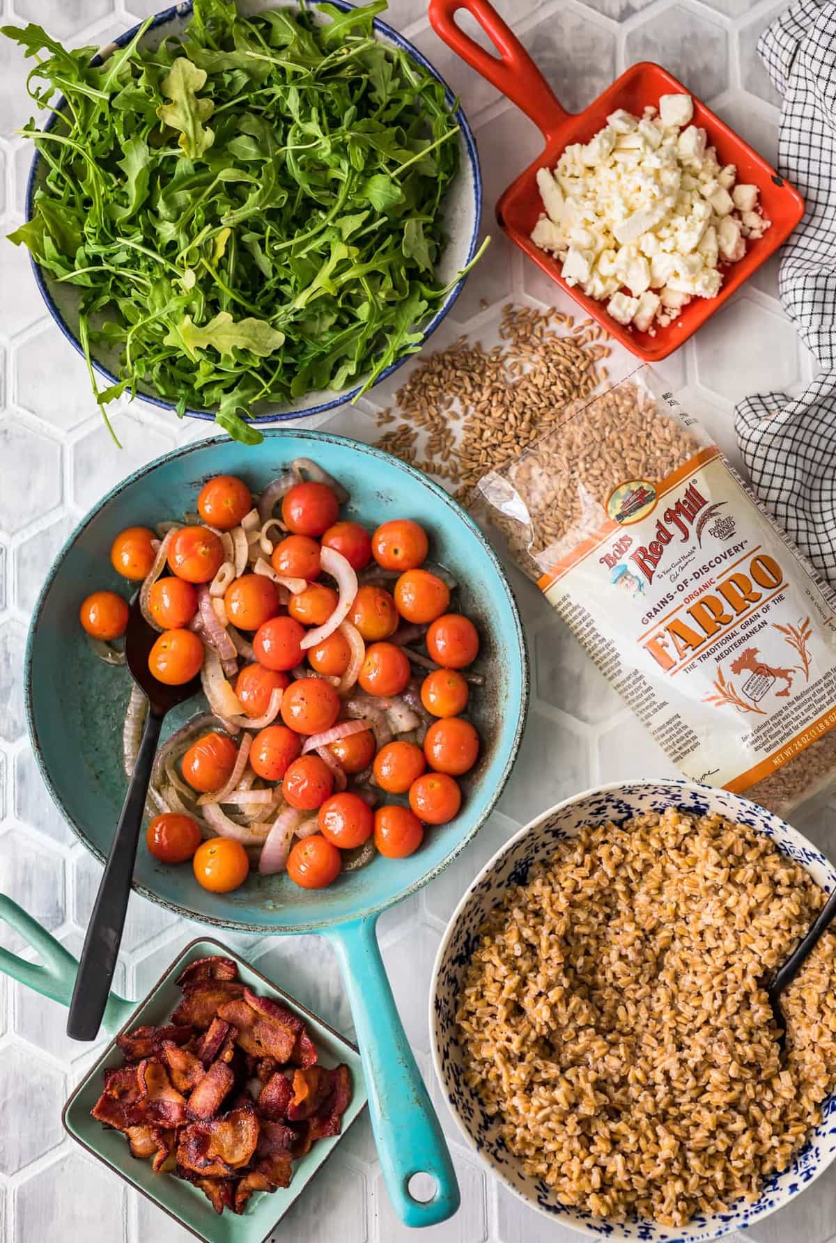 bowls of tomatoes, arugula, and farro arranged on a table