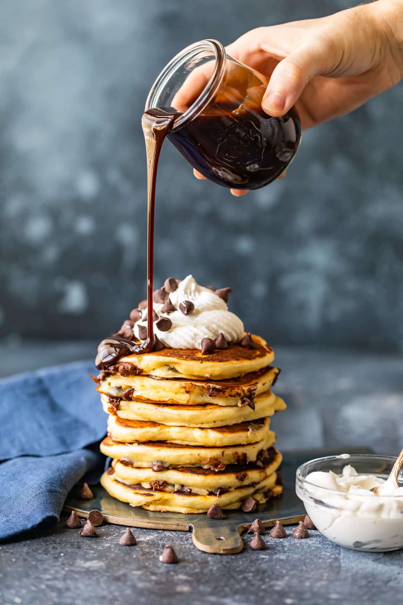 Chocolate syrup being poured over pancakes