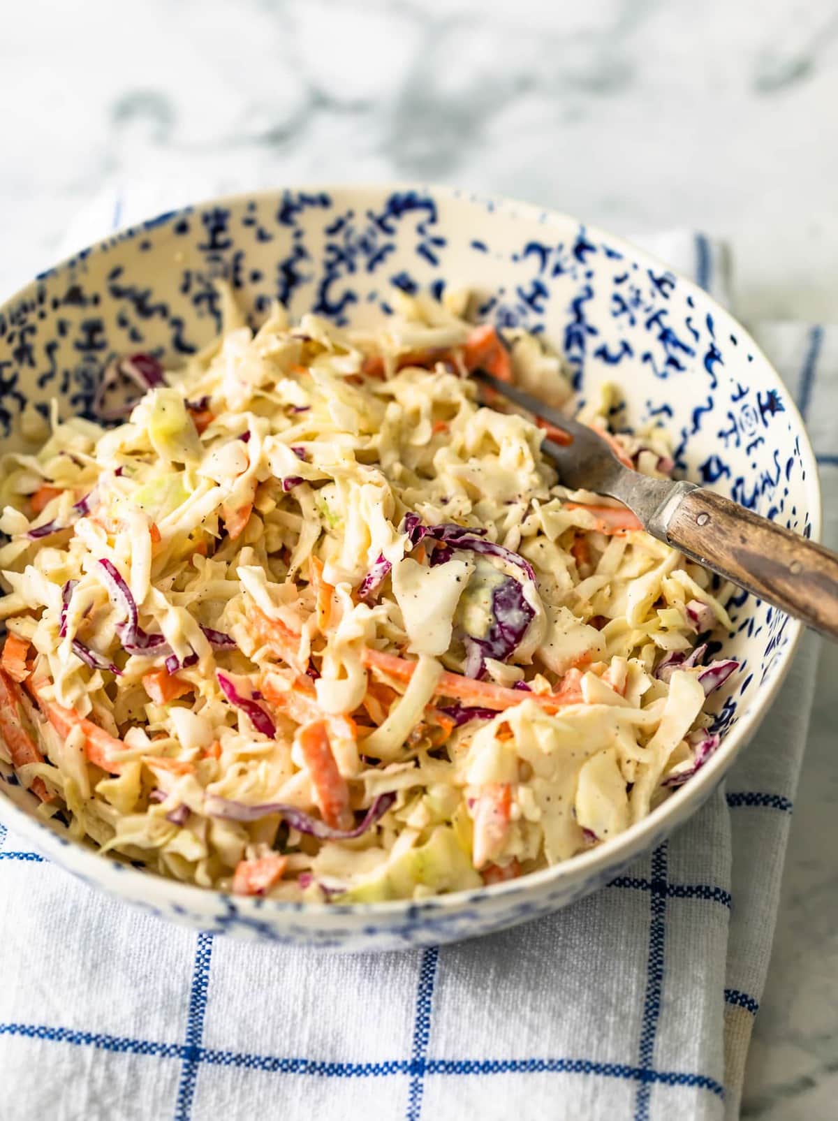 Coleslaw in a blue and white bowl with a fork.