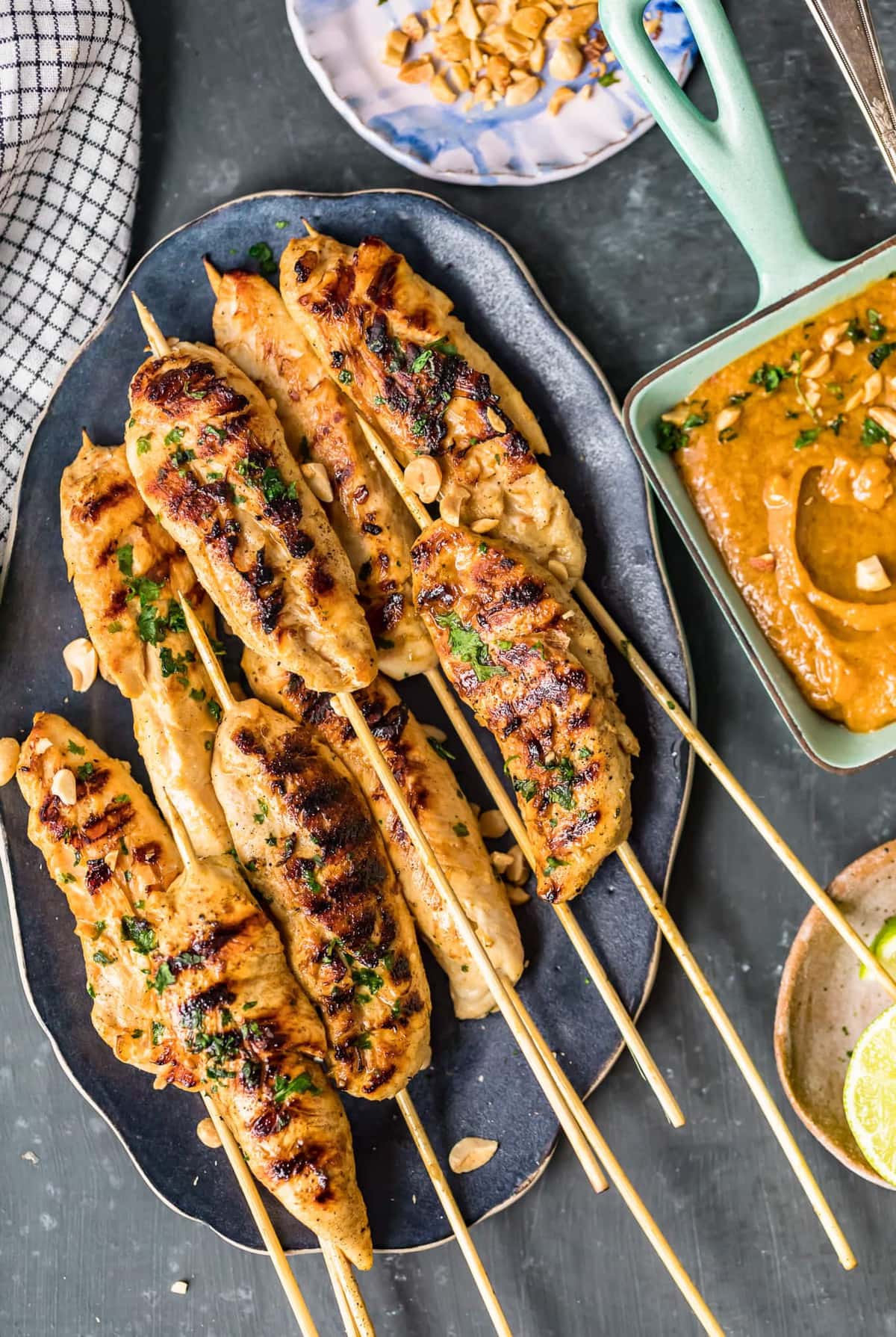 chicken skewers on a plate next to a bowl of peanut sauce