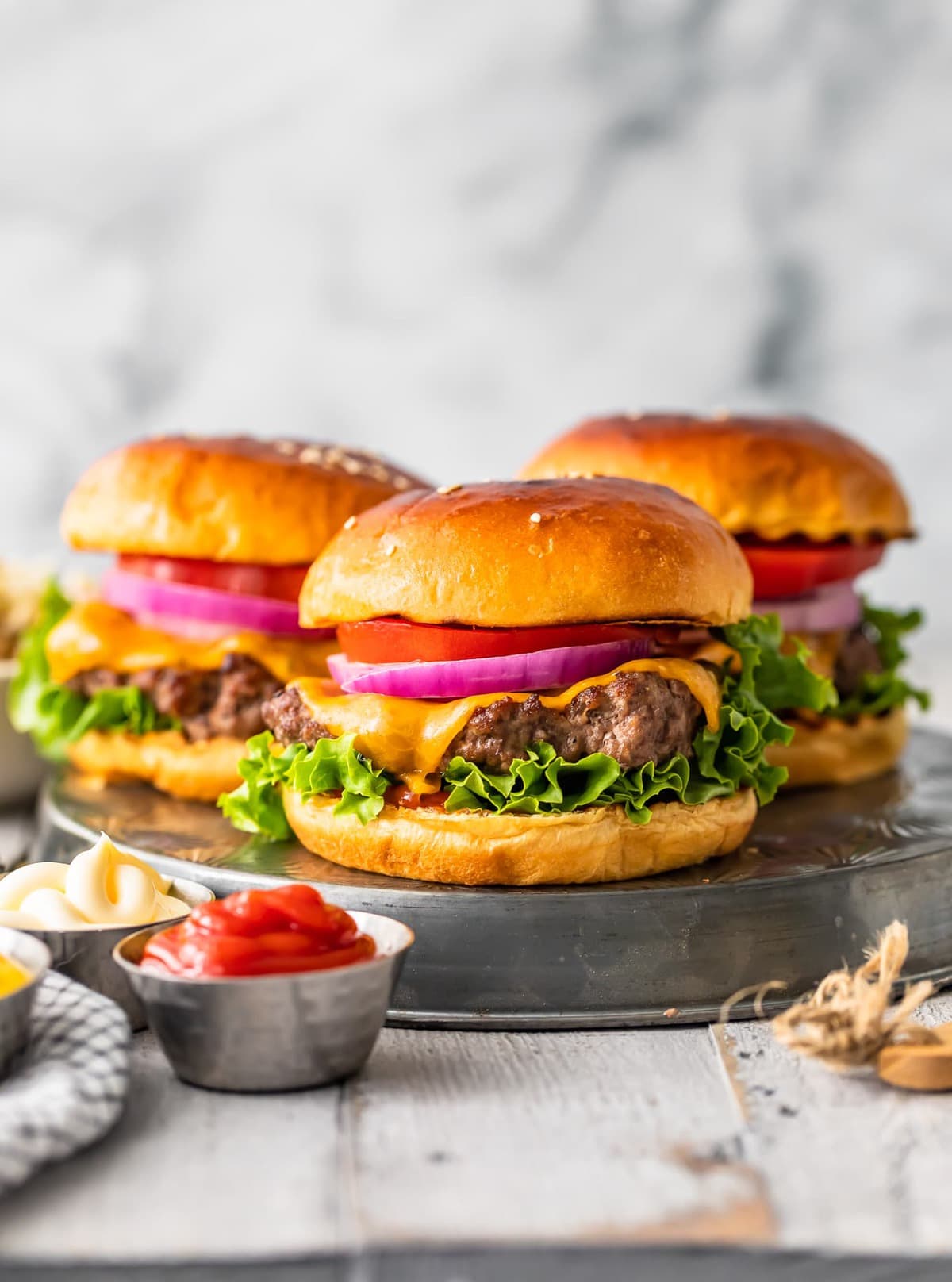 three hamburgers next to small bowls of condiments