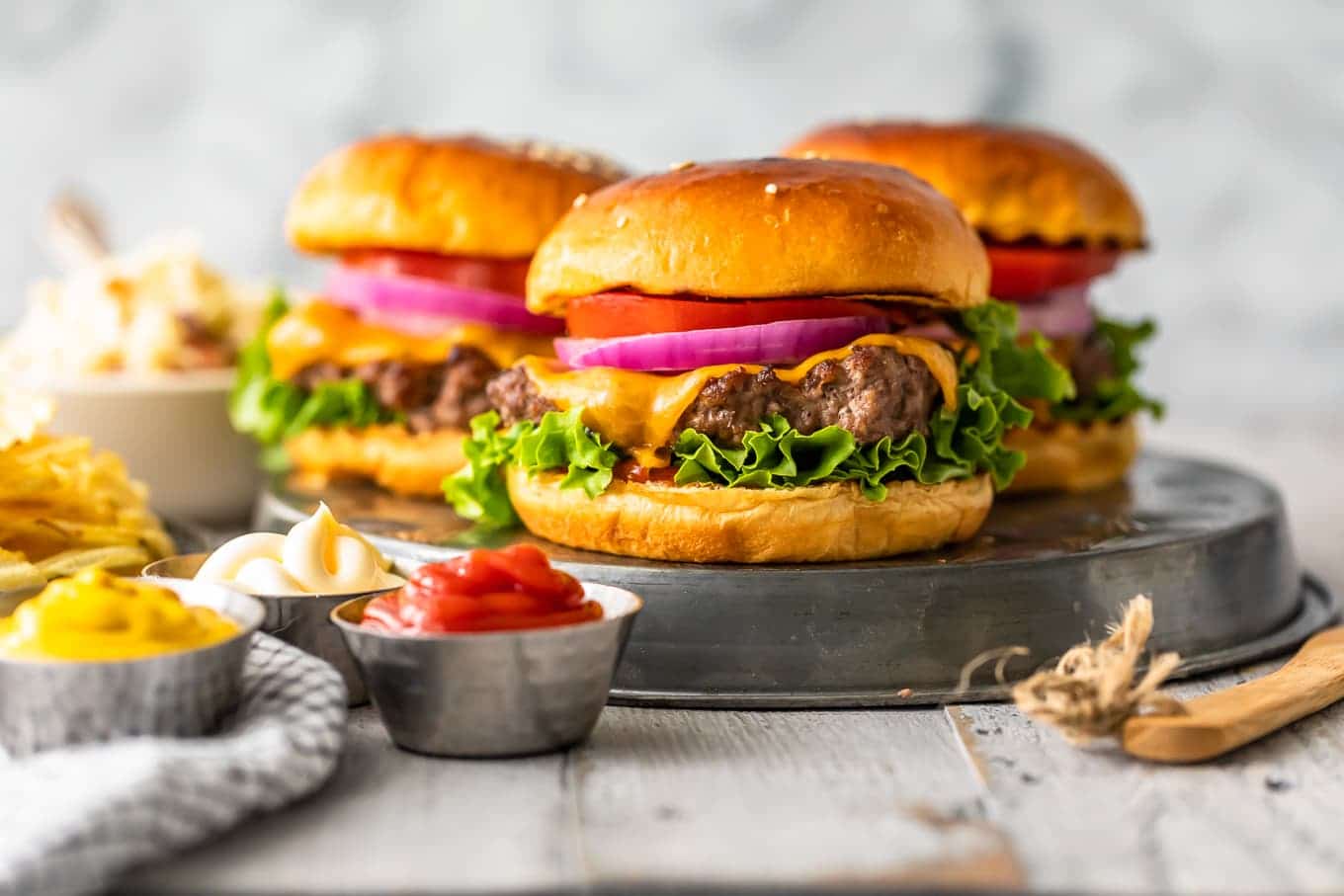 cheeseburgers, condiments, and chips on a table