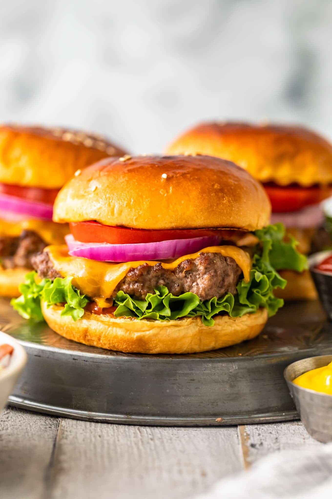 cheeseburgers topped with onions and tomatos