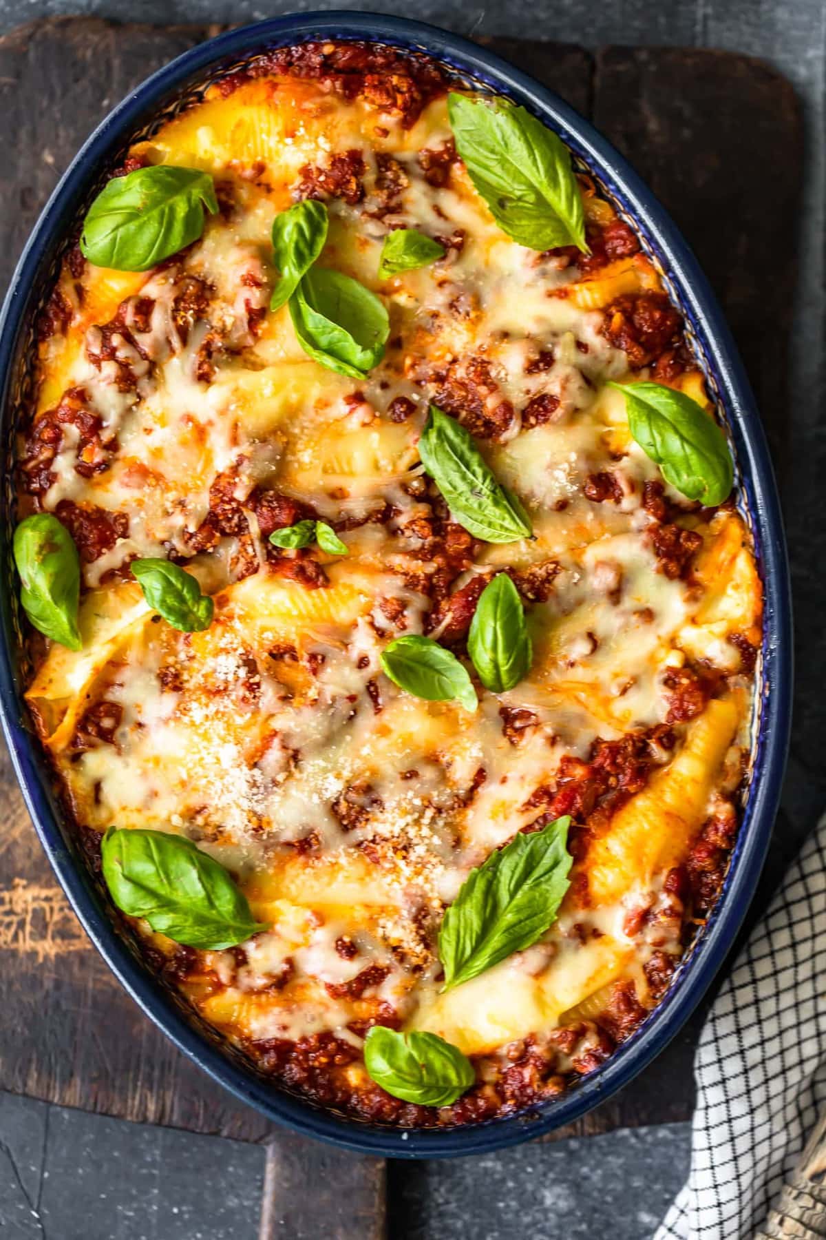 stuffed pasta shells topped with cheese and basil leaves in a casserole dish