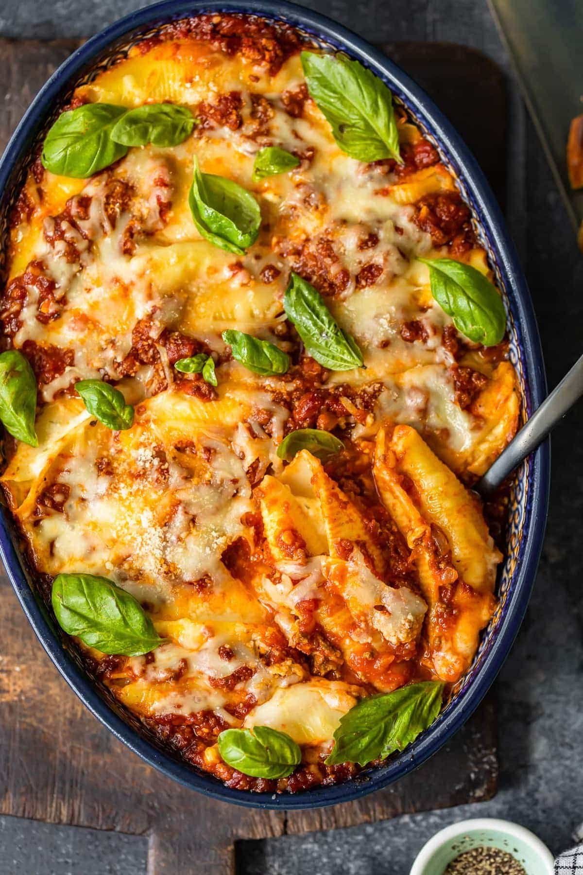 stuffed pasta shells in a casserole dish with a serving spoon