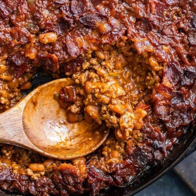 baked beans being scooped out of skillet