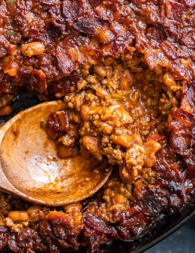 baked beans being scooped out of skillet