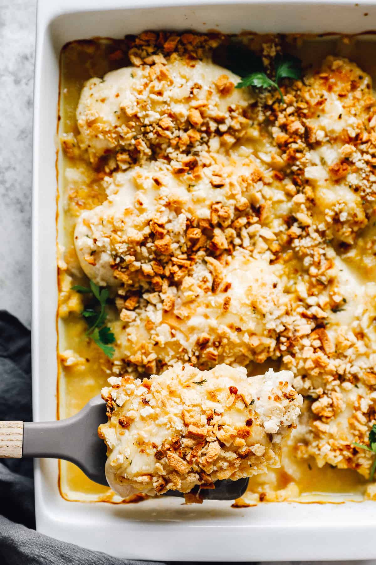 spatula lifting a piece of Swiss chicken bake topped with stuffing out of a casserole dish