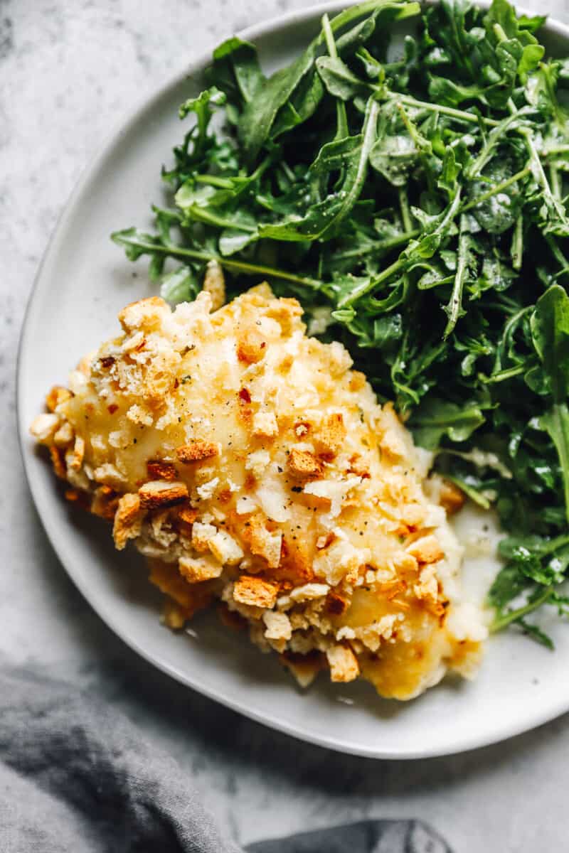 creamy cheesy Swiss chicken breast on a plate with greens 