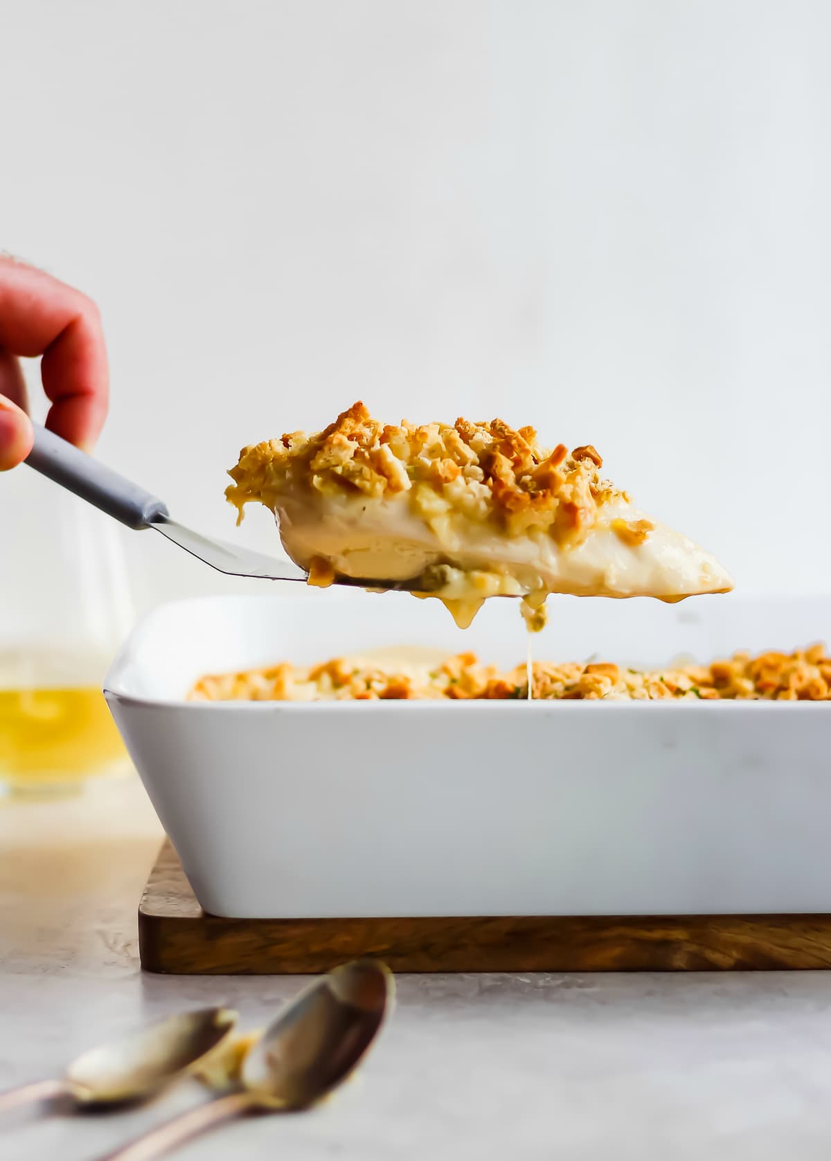 picking a piece of chicken out of the casserole dish