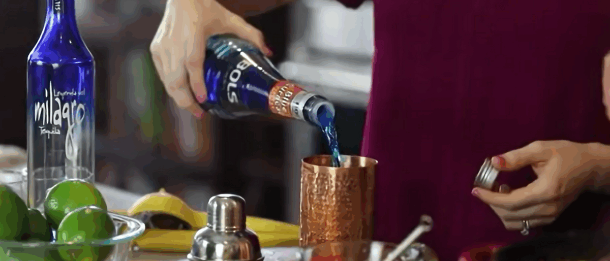 Pouring Blue Curacao into a cocktail shaker. 