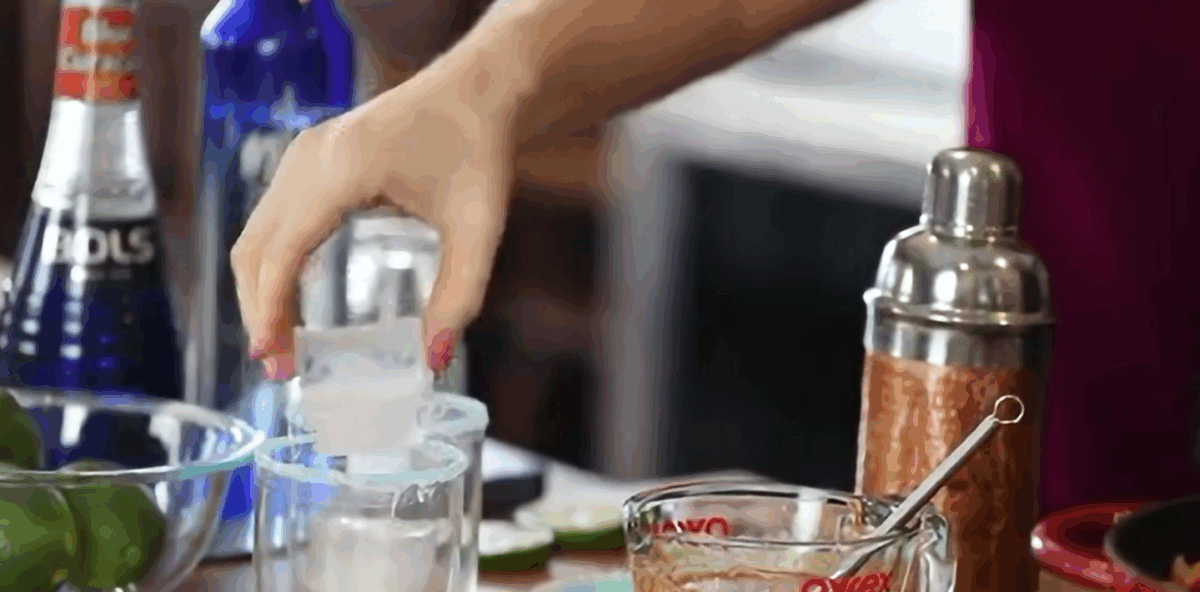 Placing ice cubes in a salt rimmed glass. 