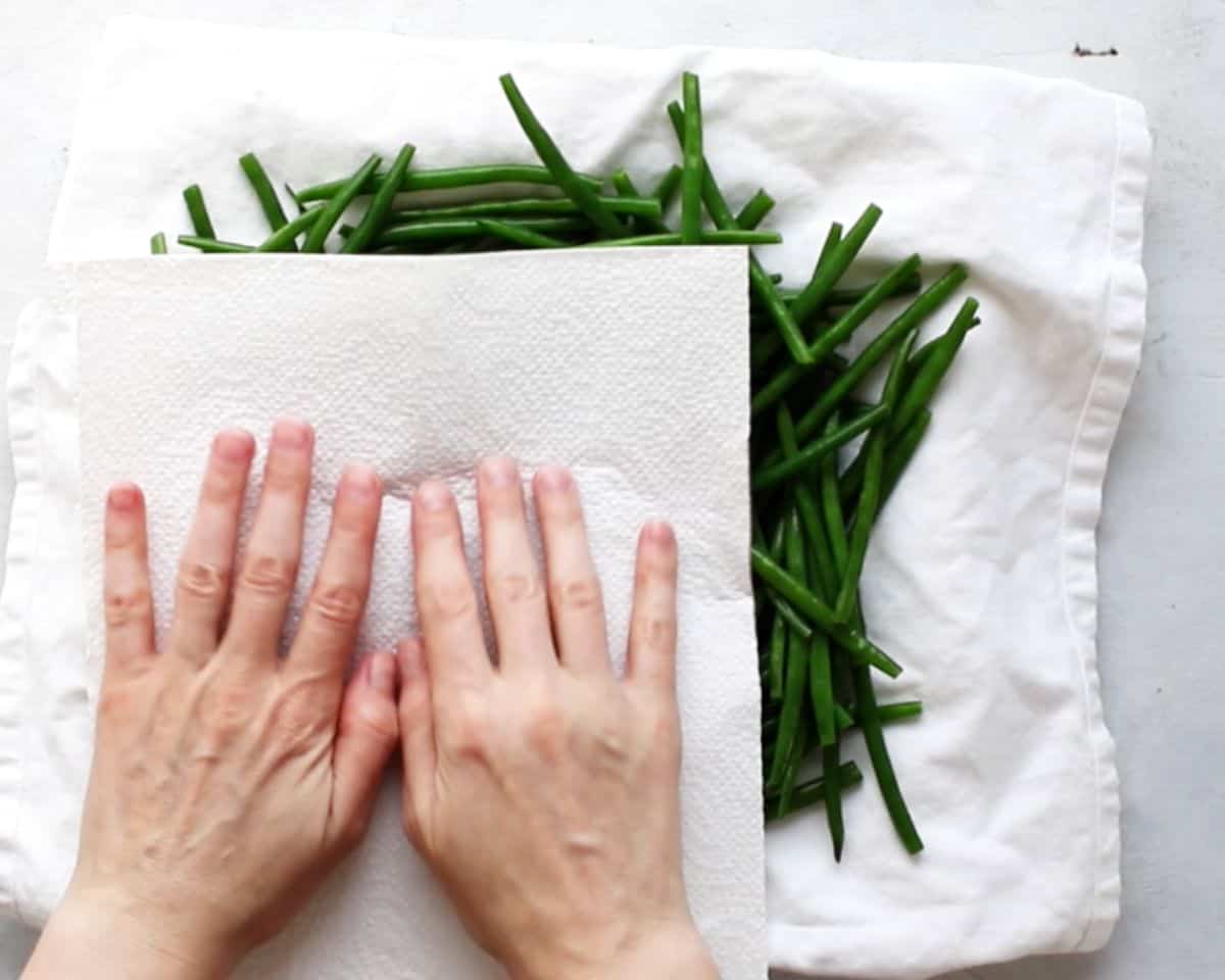 hand using a paper towel to dry green beans