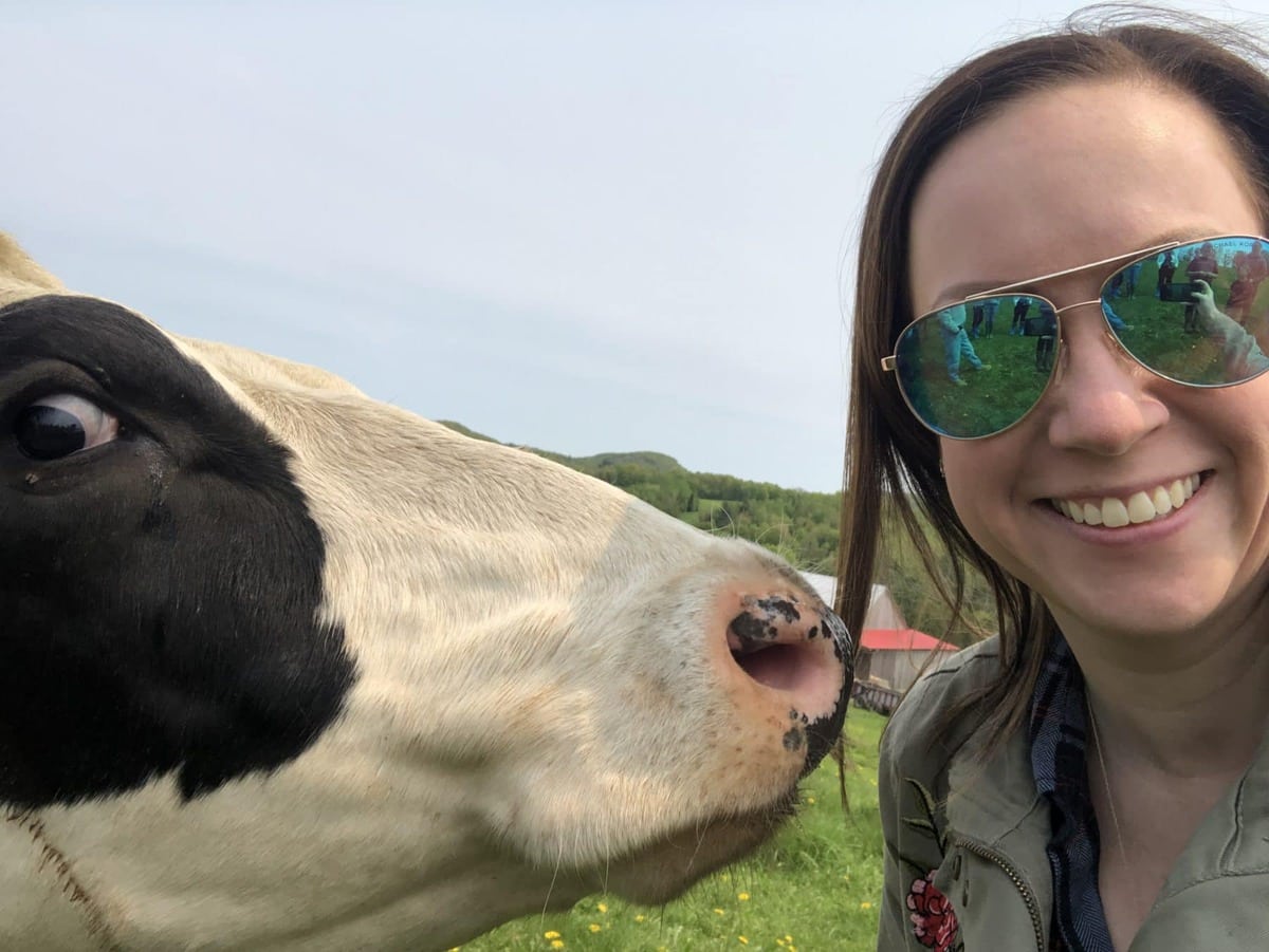 smiling with cow in field at dairy farm