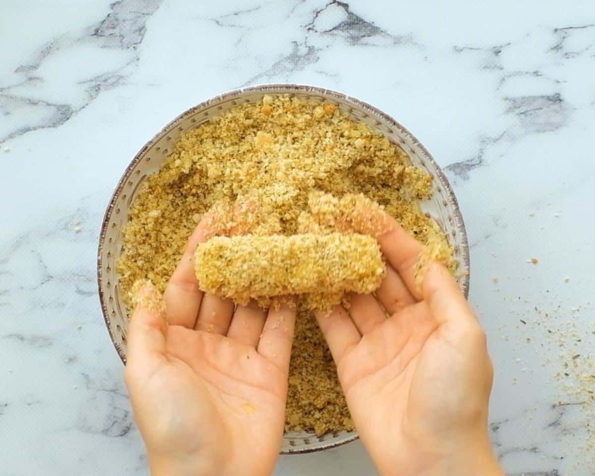Hands holding a breaded mozzarella stick.