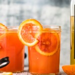 blood orange paloma drink in glass with sliced oranges