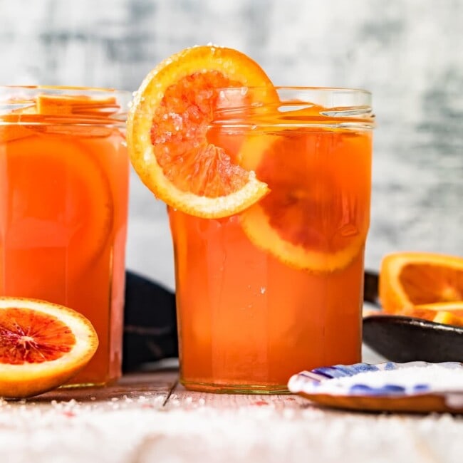 Two jars of blood orange juice on a table, perfect for making a refreshing blood orange Paloma.