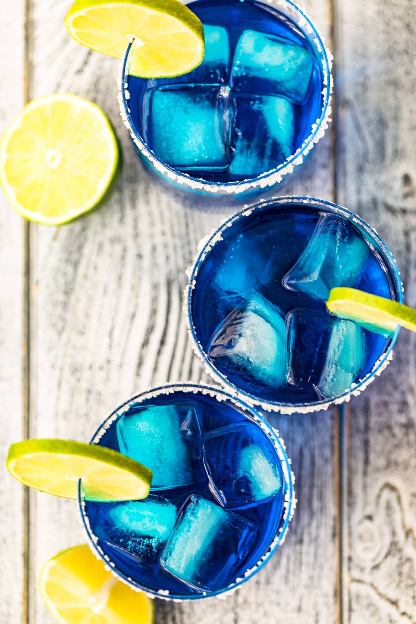 Top down shot of blue margaritas garnished with lime slices