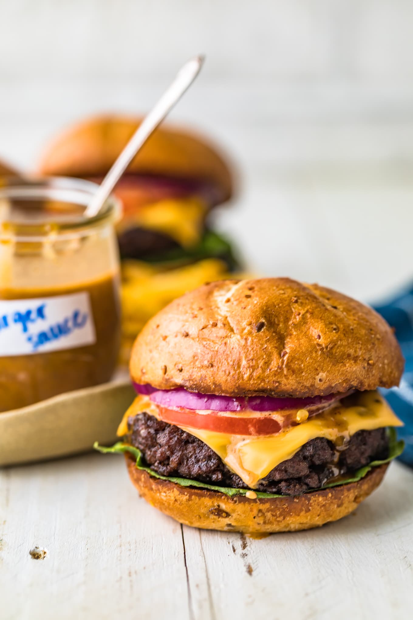 A burger topped with cheese, sauce and onion rings